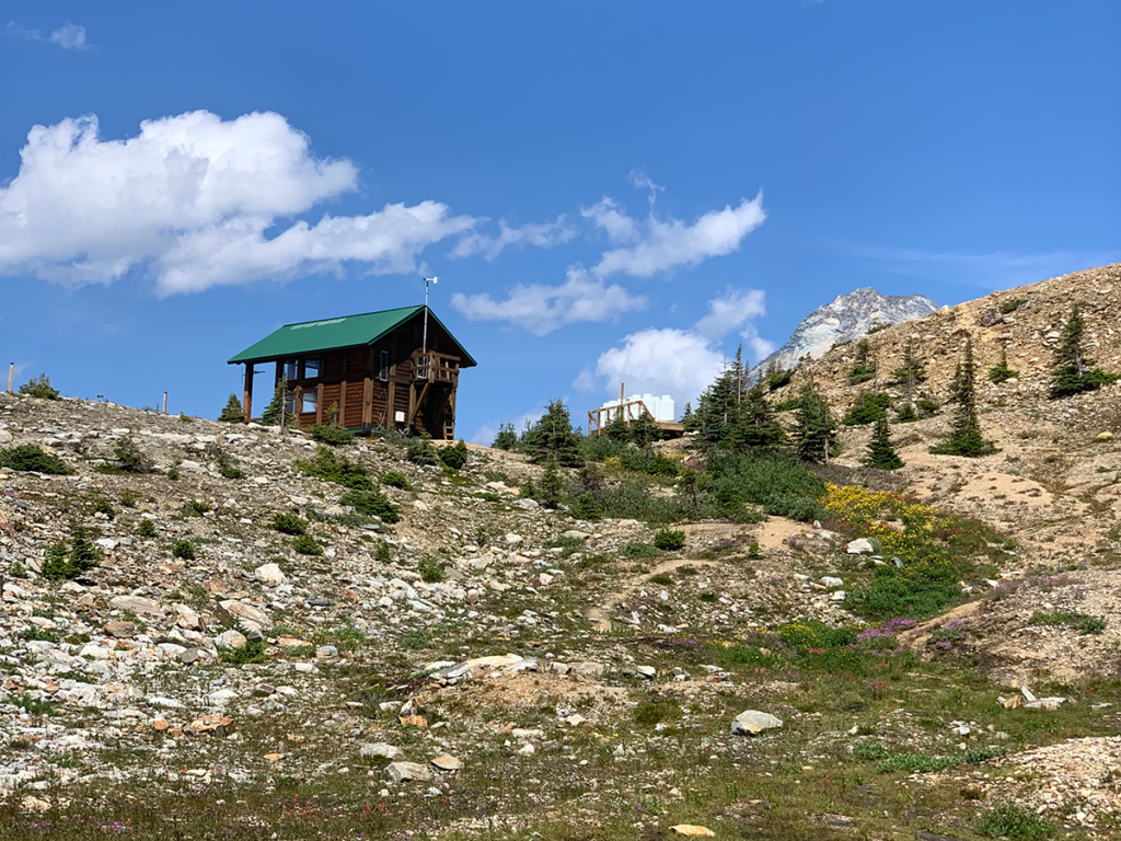 The Asulkan Cabin sitting above an alpine meadow and glacier runoff river at the top of The Asulkan Valley Trail in Canada's Glacier National Park 