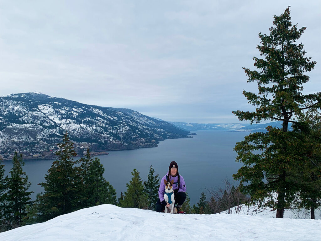 Hikes Kelowna: A woman and her dog kneeling in the snow at a lookout on a hike in Knox Park over Okanagan Lake 