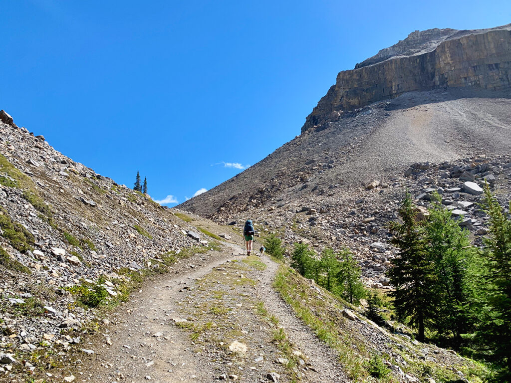 A woman hiking on a rocky trail through large mountains